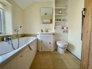 a bathroom with a tub and a toilet and a sink at Plum Tree Cottage, Burnham Market By Together Travel in Burnham Market +10 photos