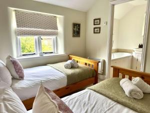 a bedroom with two beds and a window and a tub at Plum Tree Cottage, Burnham Market By Together Travel in Burnham Market