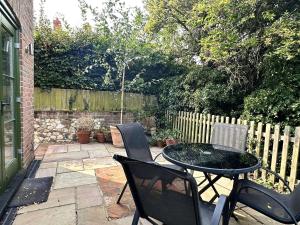 a patio with a table and chairs and a fence at Plum Tree Cottage, Burnham Market By Together Travel in Burnham Market