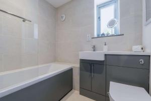 a bathroom with a tub and a sink and a toilet at FORGETMENOT COTTAGE - Wells-next-the-Sea in Wells next the Sea +19 photos