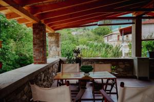 a patio with a table and chairs on a stone wall at Bridge View Cottage in Podhokhórion