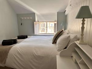 una camera da letto con un grande letto bianco con una finestra di WELL COTTAGE - Salthouse a Salthouse