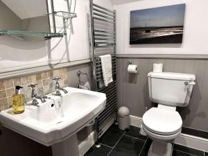 un bagno con un lavandino bianco e un water di WELL COTTAGE - Salthouse a Salthouse Altre 22 foto