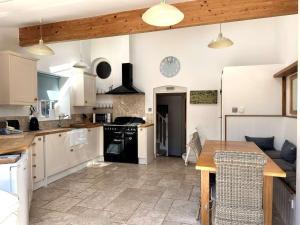 una cucina con mobili bianchi e un tavolo di legno di WELL COTTAGE - Salthouse a Salthouse