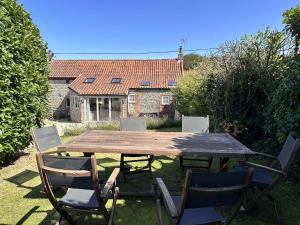 un tavolo in legno con sedie di fronte a una casa di WELL COTTAGE - Salthouse a Salthouse