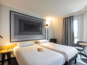 a hotel room with two beds and a flat screen tv at ibis Nancy Centre Stanislas in Nancy