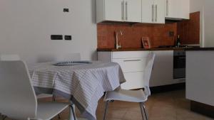 レ・グラツィエにあるAppartamento da Annamariaのキッチン(白いキャビネットと白い椅子付きのテーブル付)