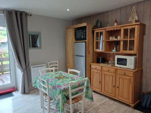 een keuken met een tafel met stoelen en een magnetron bij Entre Montagnes et Lacs in La Bresse