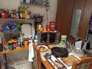 a messy kitchen with a table with a microwave at Cytau Office Wi-fi 3 Estações Trabalho 1 Dormitório Cozinha Sofá in Porto Alegre