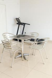 Una mesa de cristal y sillas con una computadora portátil encima. en Cozy Guest Room in Kinshasa with Balcony and Partial Air-Conditioning, en Lemba-Gaba