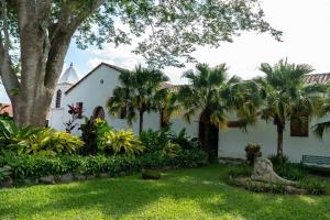 a white house with palm trees and a yard at Hostal Casa del Sol Apartamento in Suchitoto