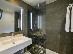 a bathroom with a sink and a glass shower at Mercure Paris La Défense in Courbevoie +113 photos