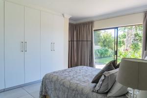 een slaapkamer met een bed en een groot raam bij Begonias Eden in Helderberg College