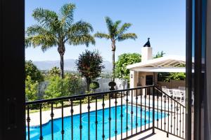 een balkon met een zwembad en palmbomen bij Begonias Eden in Helderberg College