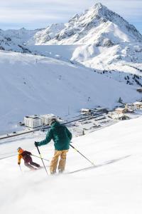 2 personnes sont en train de skier sur une montagne enneigée dans l'établissement Hotel Garni Löwen, à Silz