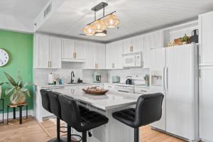 Una cocina con gabinetes blancos y una gran isla con sillas negras. en Laketown Wharf 114, en Panama City Beach