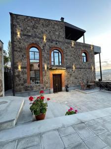 uma casa de pedra com um pátio com flores na frente em Château Byurakan Hotel em Byurakan
