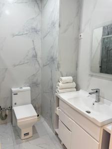 a white bathroom with a sink and a toilet at Nest one, Tashkent City in Tashkent