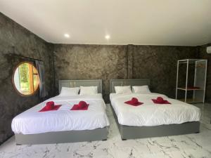 2 letti con cuscini rossi in una camera da letto di Khaosok Foresta Resort a Phanom
