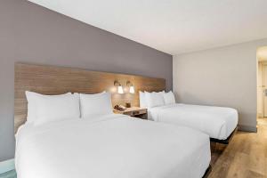 two beds in a hotel room with white pillows at The Angler Hotel Livingston, an Ascend Collection Hotel in Livingston