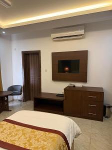 Una habitación de hotel con una cama y un televisor de pantalla plana. en The Grand Mirage Hotel, en Ma‘ābīlah