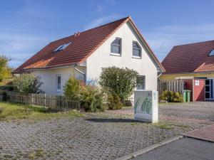 een wit huis met een koelkast op de oprit bij Stranddistel XL in Boiensdorf