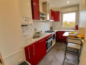 a kitchen with red cabinets and a sink at Calme & spacieux, RER A 3 min, Parking, 2 salles d'eau in Achères