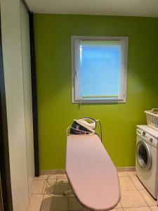 a green room with a chair and a washing machine at Maison de vacances in Ramous +9 photos