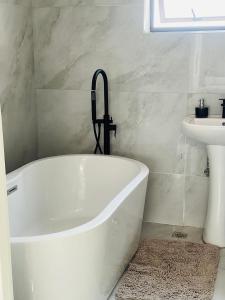 a white bath tub in a bathroom with a sink at Tranquil Ridge BnB in Blantyre