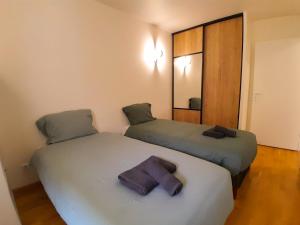 two beds sitting next to each other in a room at Calme & spacieux, RER A 3 min, Parking, 2 salles d'eau in Achères