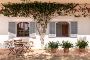 una mesa y sillas frente a una casa con un árbol en Sa Nau Agroturismo - Adults Only over 16, en Portocolom