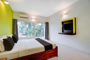 a bedroom with a bed and a tv and a window at Townhouse Morjim Beach North Goa Formerly Bay Breeze Hotels & Resorts in Chopdem +33 photos