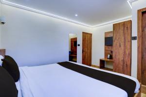 a bedroom with a white bed and wooden cabinets at Collection O Baga Beach Goa Formerly Traveller Guest House in Baga