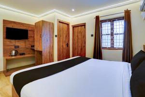 a bedroom with a large bed and a television at Collection O Baga Beach Goa Formerly Traveller Guest House in Baga