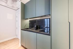 Una cocina con gabinetes blancos y encimera. en Suites Madrid Centro, en Madrid