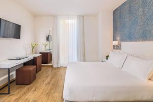 Una habitación de hotel con una cama grande y un escritorio. en H10 Raco del Pi, en Barcelona