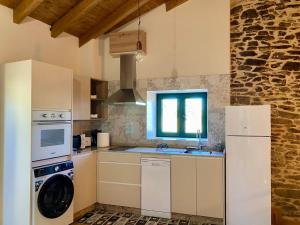 a kitchen with a washing machine and a sink at Casa Veracruz Sanabria in Puebla de Sanabria +13 photos