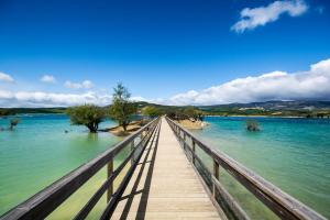 a wooden bridge over a body of water at Amplia casa para desconectar con vistas al lago in Lerate