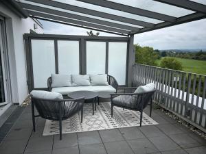 a patio with a couch and chairs on a balcony at Penthouse Apartment in Gießen