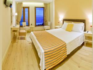 a bedroom with a large bed and two windows at Arktos Hotel in Ioannina
