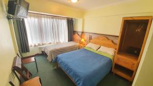 a hotel room with two beds and a television at Hosteria Chalp in Ushuaia