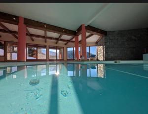 a large swimming pool with water in a building at Appartement cosy Peisey Les Arcs 6-8 pers - piscine sauna - en face des pistes in Peisey-Nancroix