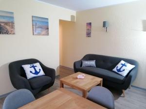 a living room with two chairs and a couch at Hotel Pension garni Haus am Strand in Norddeich +2 photos