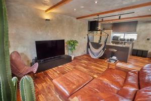 a living room with a leather couch and a flat screen tv at COCO VILLA 九十九里一宮-Sauna- in Ichigaya