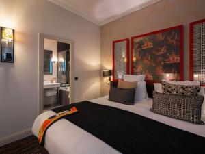 a bedroom with a large bed and a bathroom at Le Stendhal - Vendôme in Paris