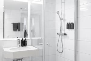 a white bathroom with a shower and a sink at Home Hotel Majoren in Skövde +39 photos