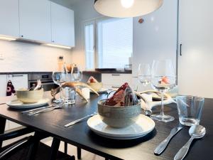 Una mesa de madera con platos y copas de vino encima. en Villa Kotikuja, en Rovaniemi