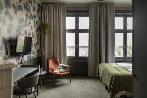 a bedroom with a bed and a desk and window at Home Hotel Majoren in Skövde