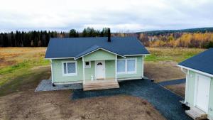 una casa verde con techo azul en un campo en Villa Kotikuja, en Rovaniemi