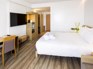 a hotel room with a large bed and a desk at Novotel Campo De Las Naciones in Madrid